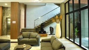 A modern lobby with a staircase, seating area, and large windows. - Long Beach Hotel Pangandaran (Pangandaran)
