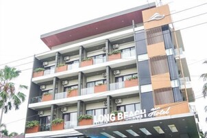 Un hotel de varios pisos con balcones, unidades de aire acondicionado y un letrero que indica que es un hotel.