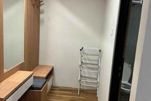 Baño pequeño con tocador de madera, toallero y un inodoro a la vista a través de una puerta abierta.