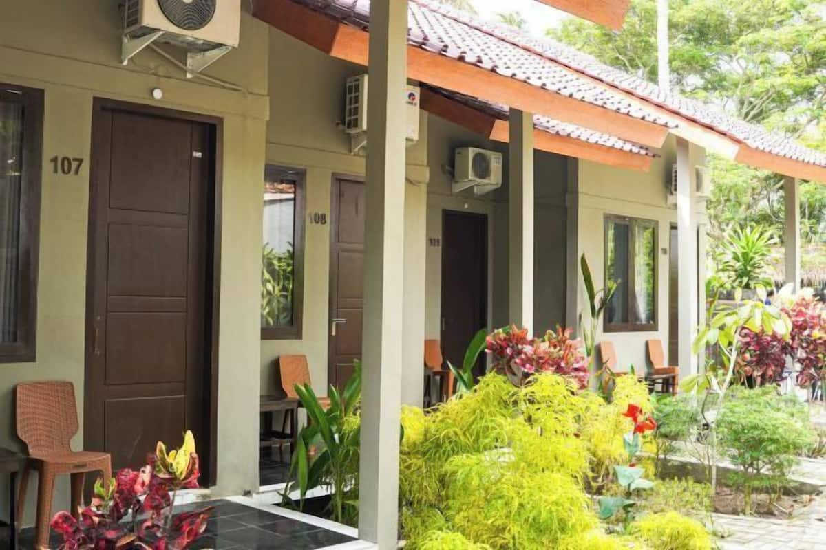 Un edificio con porte numerate, sedute all'aperto e un'area giardino con diverse piante.