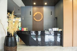 A reception desk with a black marble top, a wooden vertical panel, and a circular wall decoration.