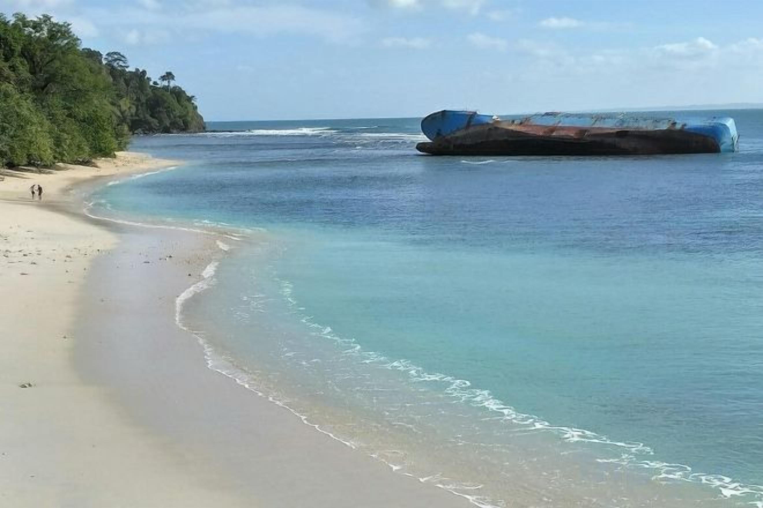 Una playa con agua cristalina, un gran naufragio y una zona boscosa.
