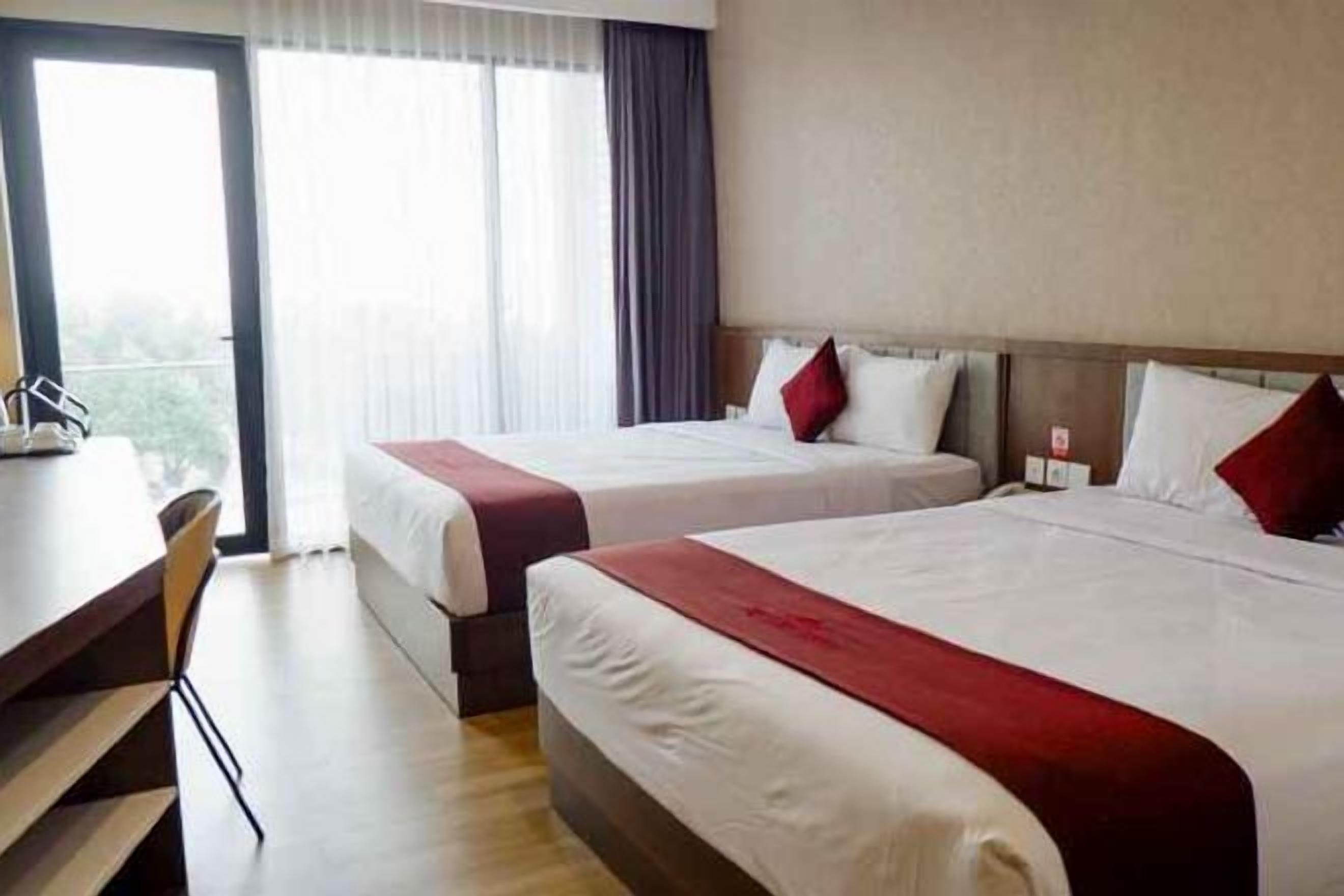 Une chambre d’hôtel avec deux lits, un bureau et une chaise.