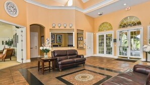 A spacious lobby with a brown leather sofa, a round rug, and a reception desk.