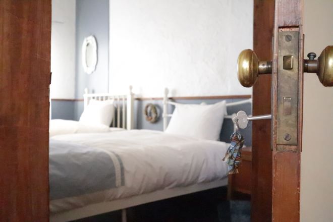 A hotel room with a bed, a bedside table, and a wall-mounted clock.