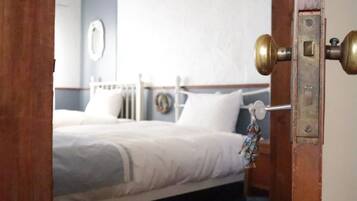 A hotel room with a bed, a bedside table, and a wall-mounted clock.