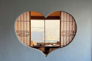 A heart-shaped window with traditional Japanese paper patterns, a desk, and bookshelves. - Mojiko guesthouse PORTO (Kitakyushu)
