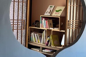 A circular view of a room with a wooden bookshelf containing books and a small whiteboard. - Mojiko guesthouse PORTO (Kitakyushu)