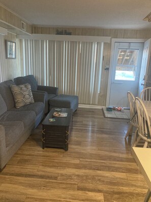 A living room with a sofa, a coffee table, and a dining area with chairs.