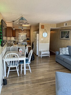 A compact living space with a dining area, kitchenette, and a seating area with a sofa.