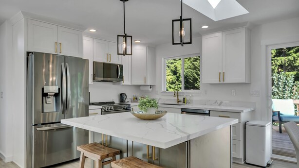 A modern kitchen with a central island, stainless steel appliances, and wooden stools.