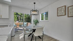 A modern kitchen with white cabinetry, a round dining table with chairs, and a hanging light fixture.