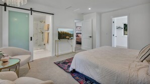 A modern bedroom with a large bed, a chandelier, and a walk-in closet.
