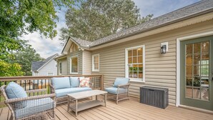 Eine überdachte Terrasse mit Korbmöbeln, einem Tisch und einem Mülleimer.