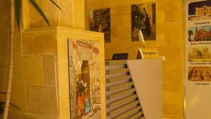 A reception area with a staircase, a reception desk, and informational posters on the walls. - Pyramids On The Spot Inn (Giza)