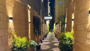 A narrow alleyway with potted plants on either side, a sign for 'PYRAMIDS ON THE SPOT VIEW', and a building in the background. - Pyramids On The Spot Inn (Giza)