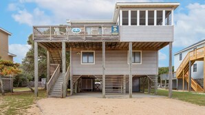 A two-story wooden building with a balcony and a covered entrance. - Saltwater Pool, Bar & Ocean Views – Duck OBX (Duck)