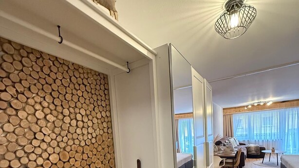 Un intérieur moderne avec un mur en bois brut, un coin repas avec une table et des chaises, et un lit offrant une vue agréable.
