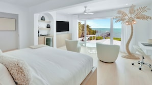 Habitació d'hotel moderna amb un llit gran, escriptori, cadira, televisió i vista al mar.