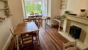 A dining area with a wooden table and chairs, a chandelier, and a fireplace. - Fairhaven Stay (Betws-Y-Coed)
