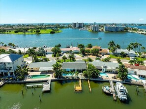 Puerto deportivo con barcos amarrados, piscina y edificios residenciales con palmeras.