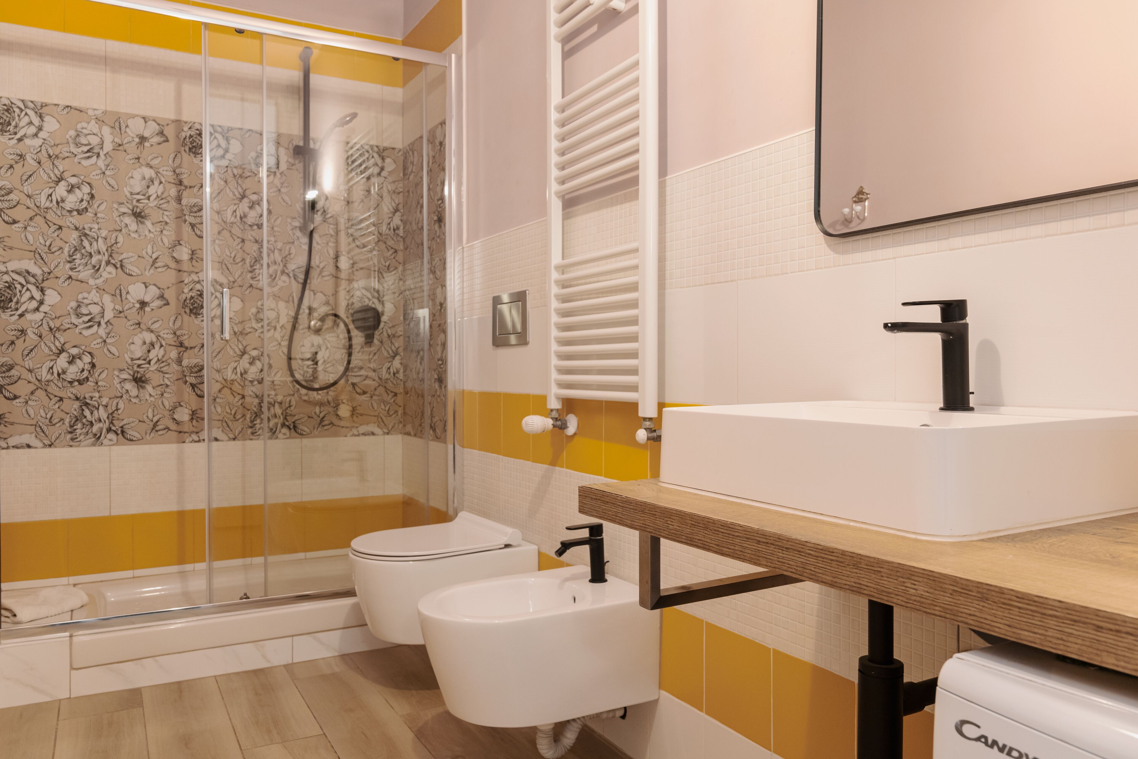 A bathroom with a glass shower enclosure, a white sink, and a toilet.