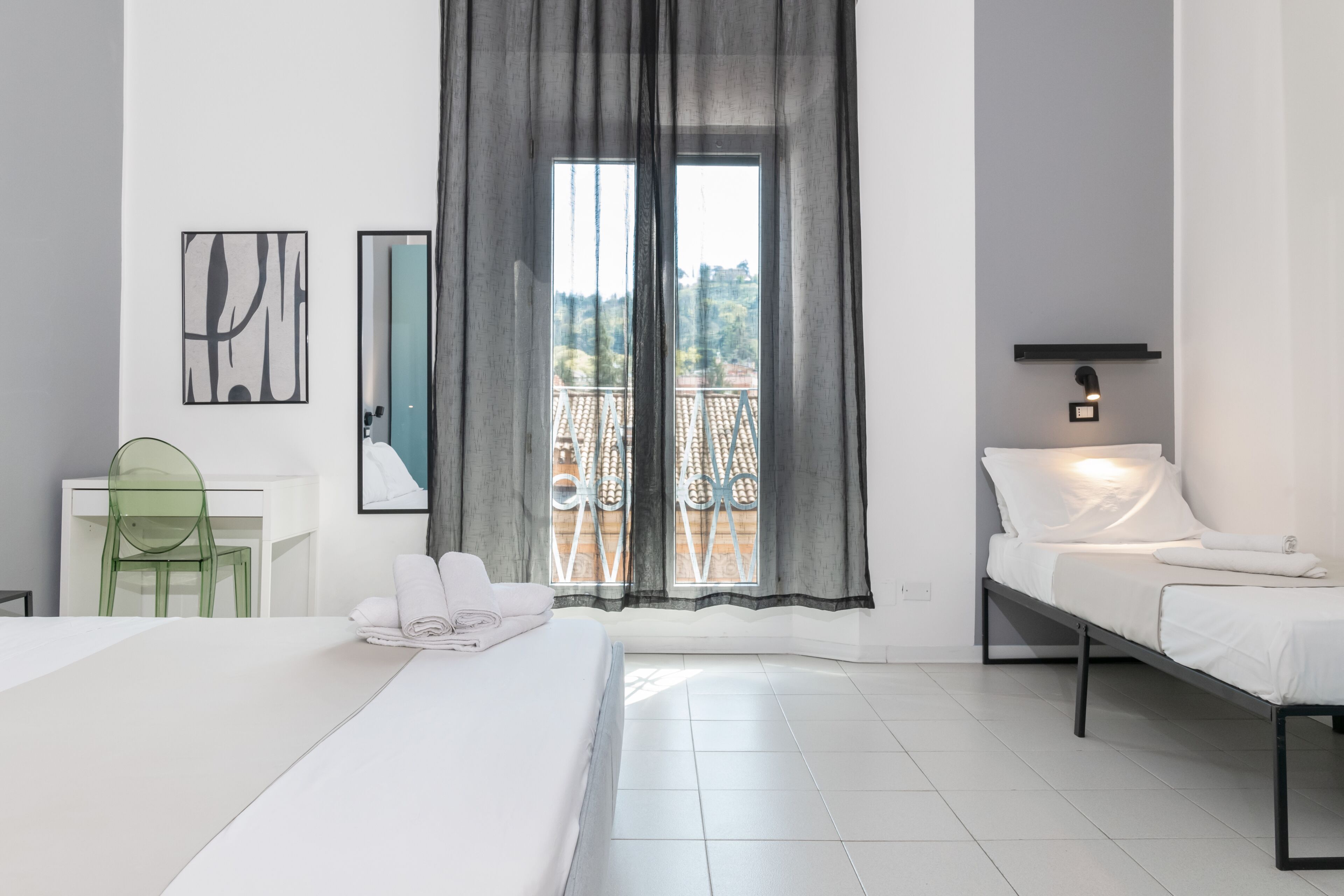 Une chambre d’hôtel équipée d’un lit, d’un bureau, d’une chaise, d’un balcon avec vue et d’une lampe fixée au mur.