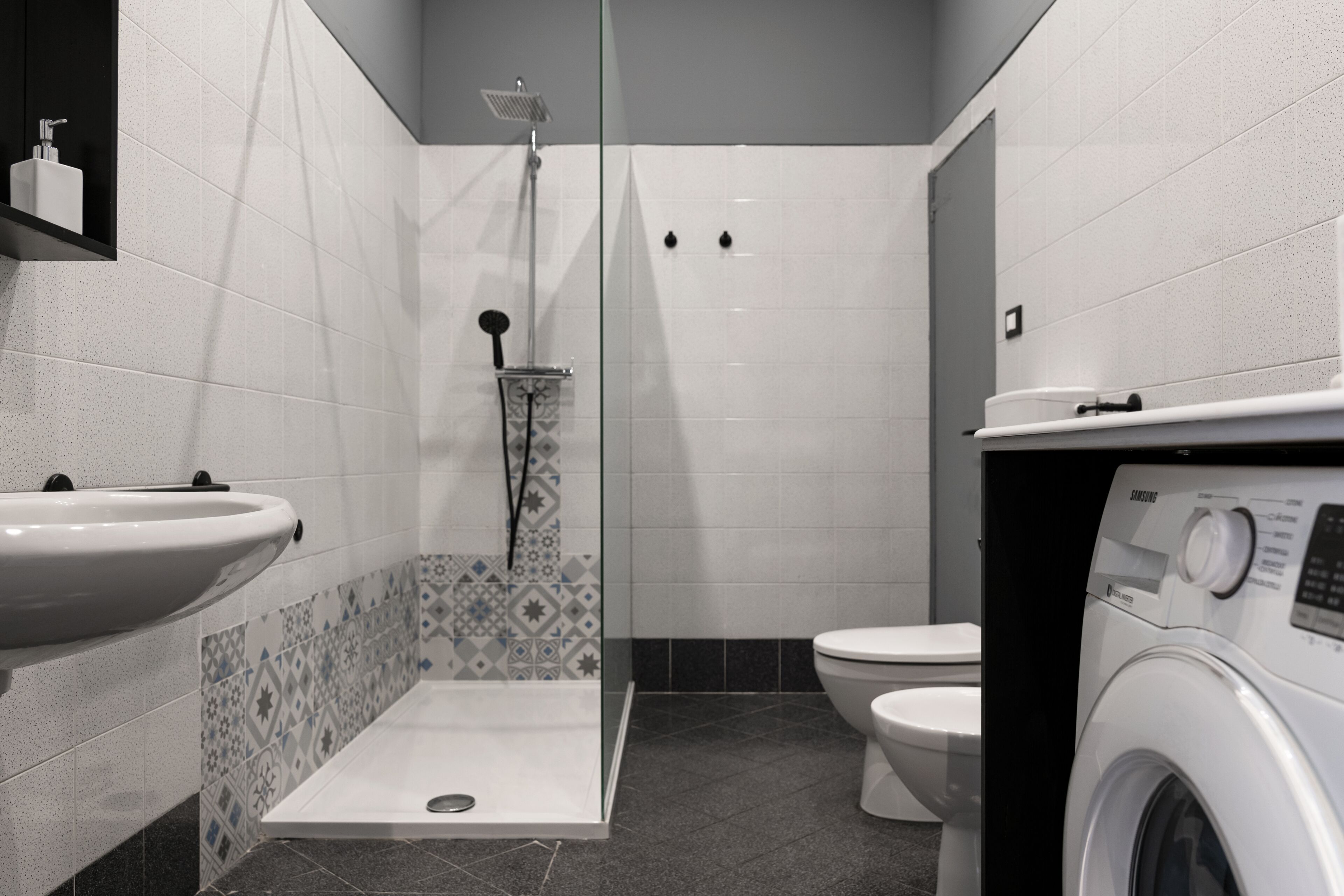 Un baño con ducha, inodoro, lavamanos y lavadora.