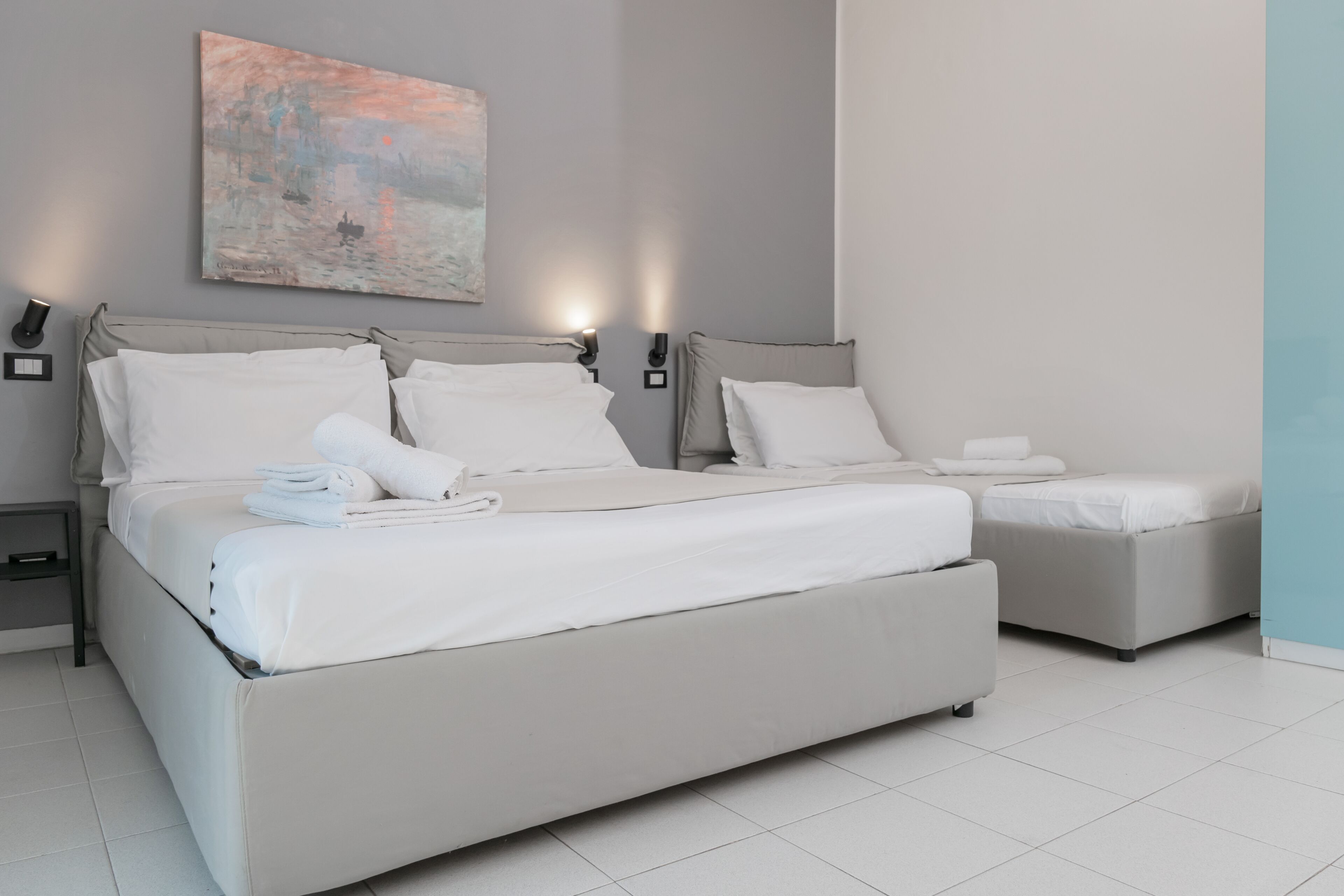 Ein modernes Schlafzimmer mit einem großen Bett, einem kleineren Bett und einem Nachttisch.