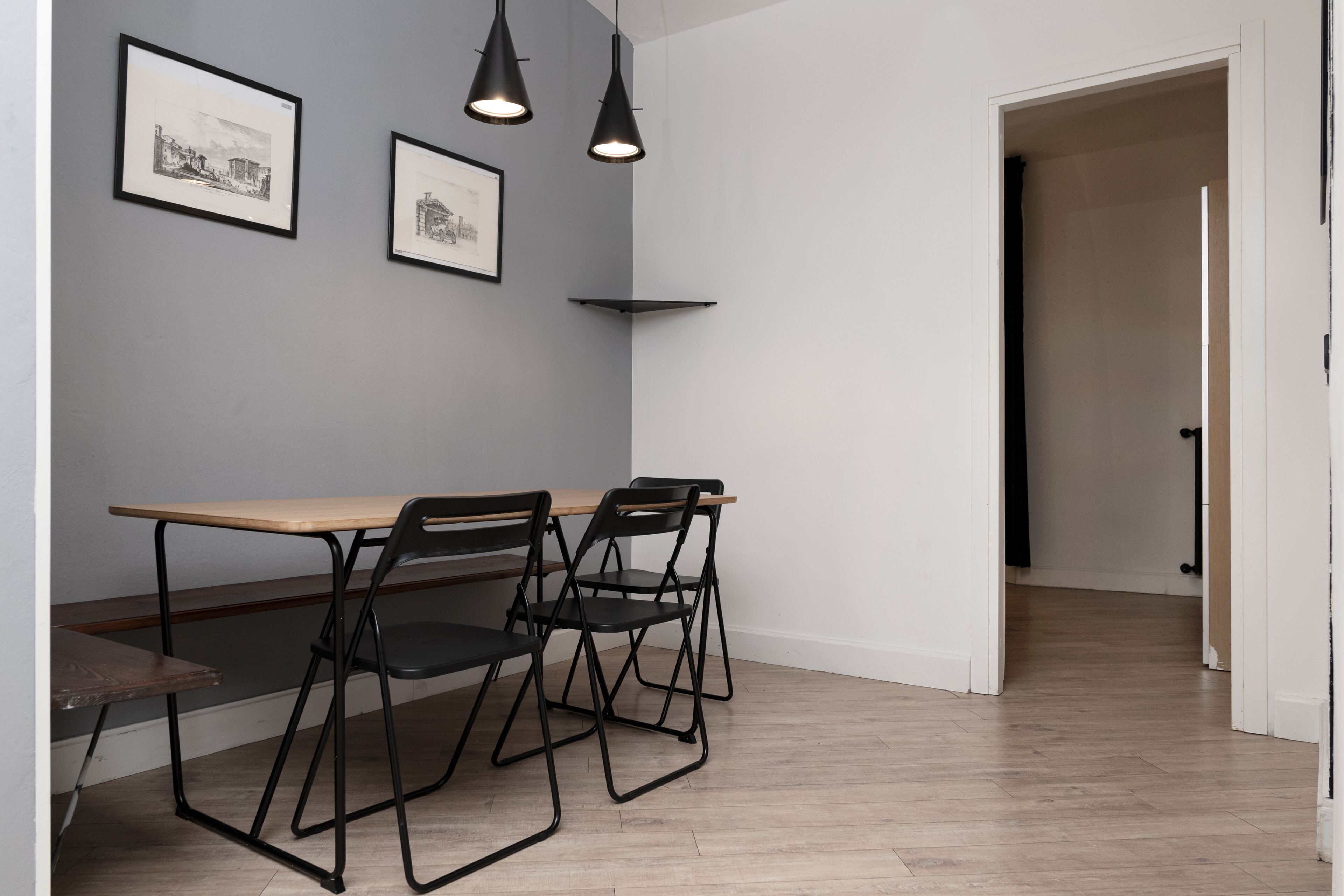 Un comedor con mesa y sillas, cuadros en la pared e iluminación colgante.