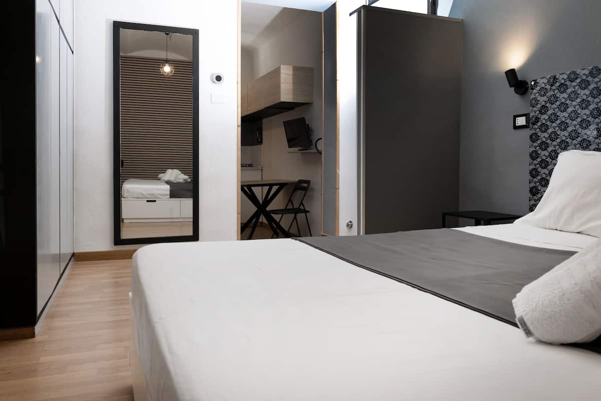 A modern bedroom with a bed, a desk, and a wardrobe.
