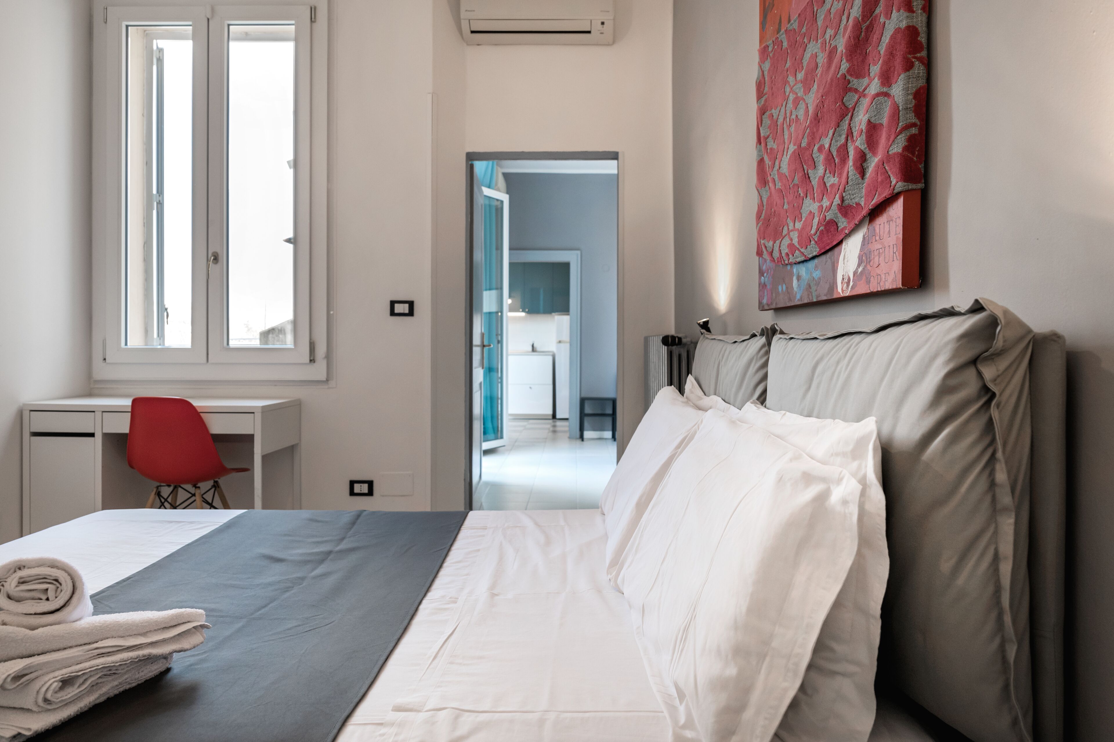 Ein Hotelzimmer mit Bett, Schreibtisch, Stuhl und einem Gemälde an der Wand.