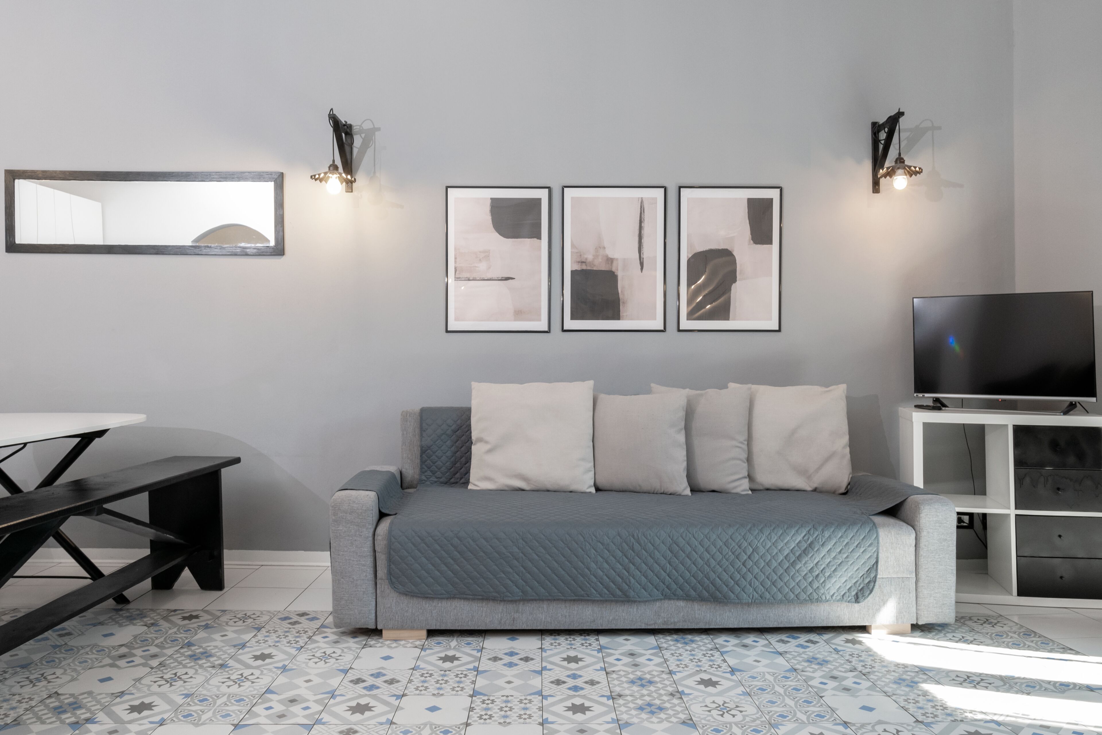 Una sala de estar moderna con un sofá, un televisor, una mesa de comedor y obras de arte en la pared.