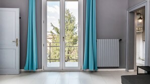 A room with a sliding glass door to an outdoor balcony, a radiator, and a ceiling-mounted air conditioning unit. - Saragozza Apartments (Bologna)