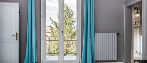 A room with a sliding glass door to an outdoor balcony, a radiator, and a ceiling-mounted air conditioning unit.