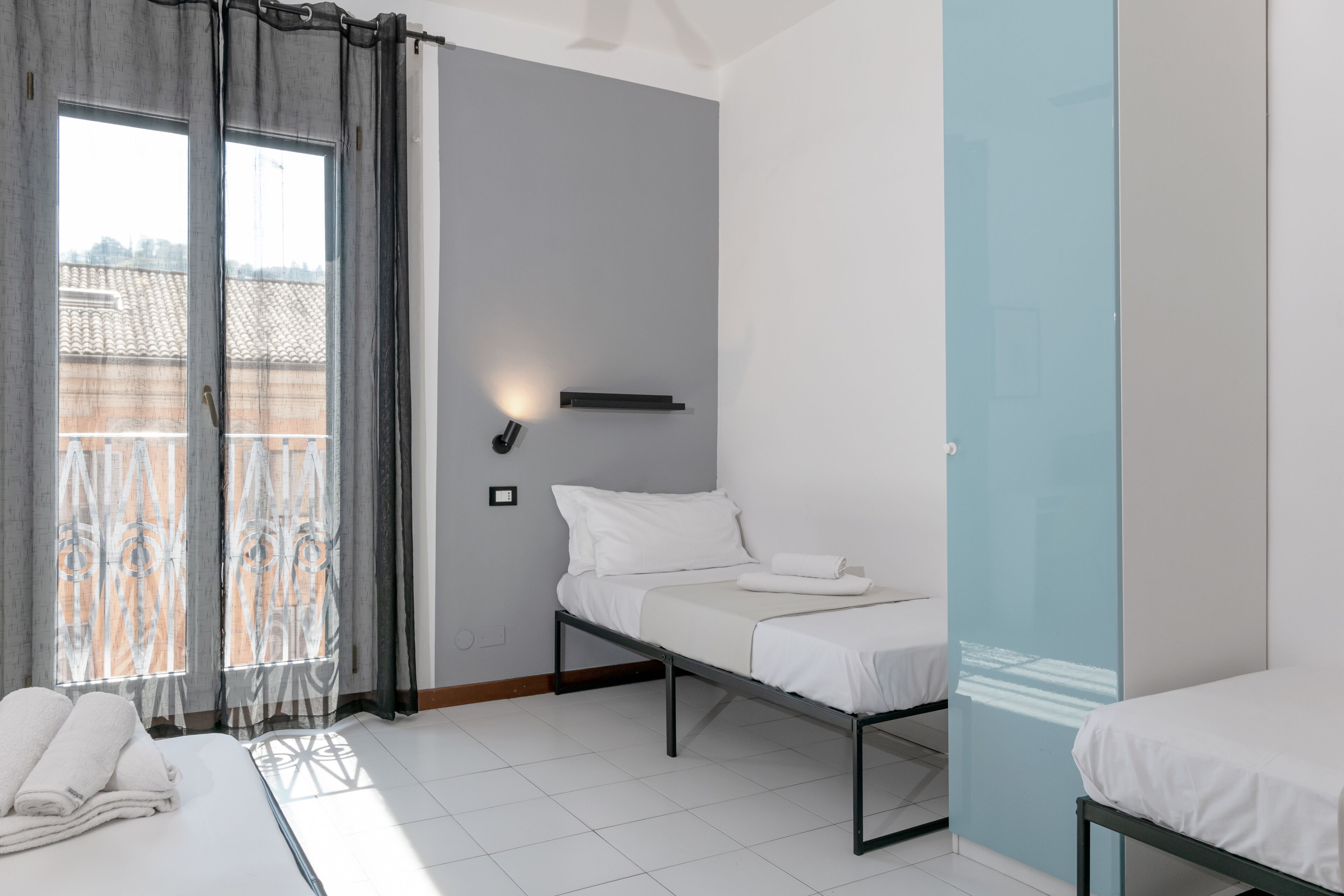 Una habitació d'hotel moderna amb un llit, una taula de nit, una làmpada penjada a la paret i vistes a l'exterior.