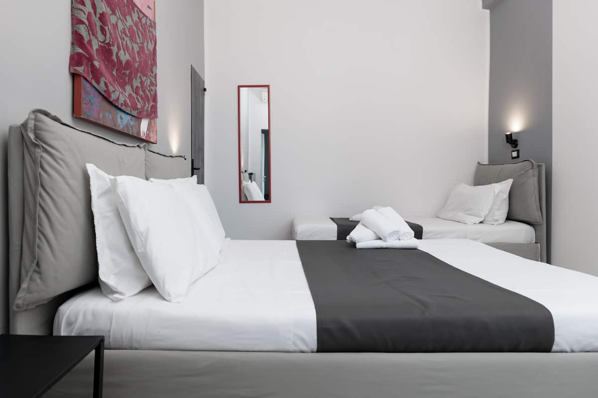 A hotel room with a large bed, two bedside tables, a mirror, and a wall-mounted artwork.