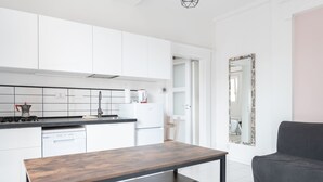 A modern kitchen with white cabinets, a wooden table, and a grey sofa. - Saragozza Apartments (Bologna)