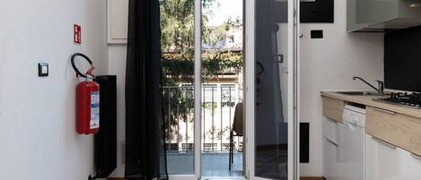 A modern kitchen with a dishwasher, a fire extinguisher, and a sliding glass door leading to a balcony.