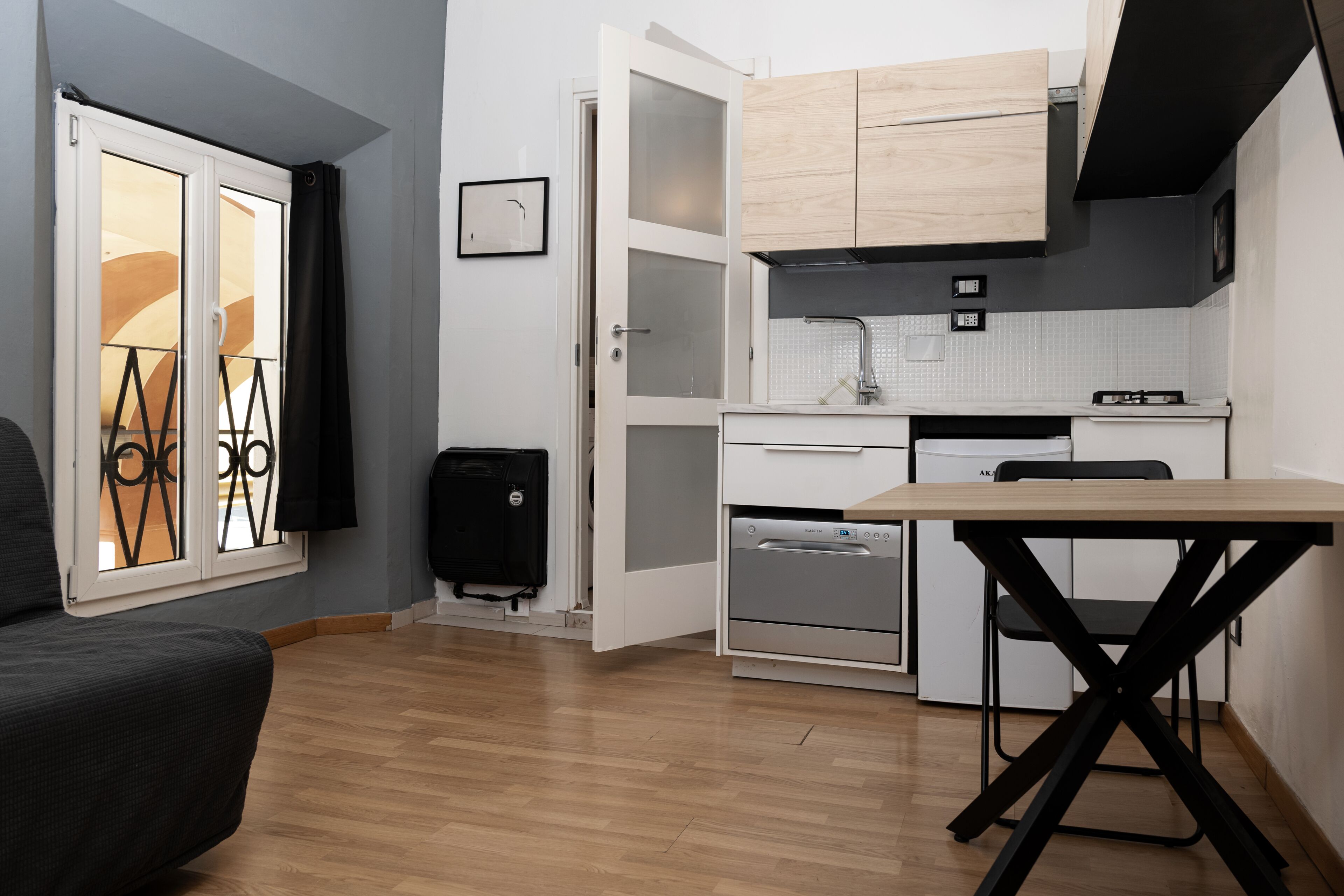 A compact kitchen with a dining table, built-in oven, and a small refrigerator.