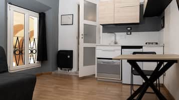 A compact kitchen with a dining table, built-in oven, and a small refrigerator.
