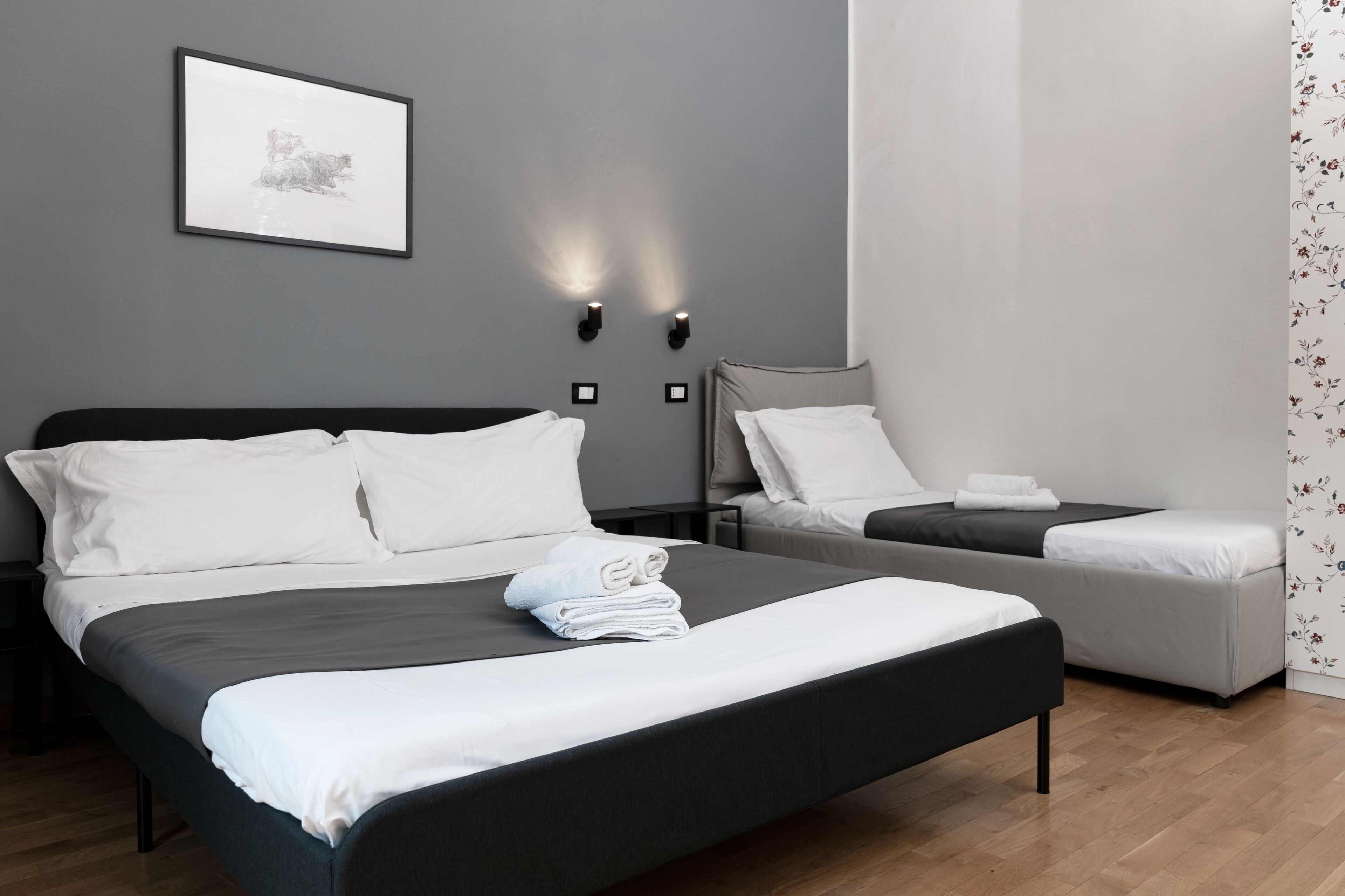 A modern hotel room with a large bed, a smaller bed, and a nightstand.