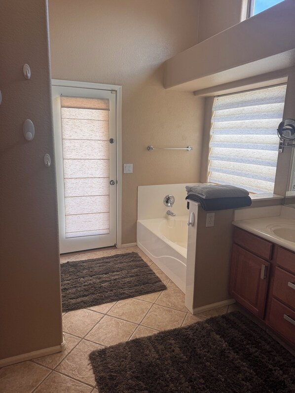 A bathroom with a bathtub, a window with blinds, a towel rack, and a shower curtain.