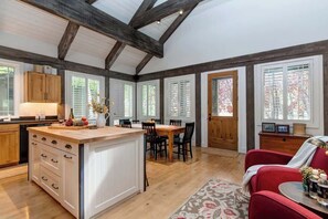 A spacious kitchen with wooden beams, a dining area, and a red sofa. - Abode at West Ketchum Farmhouse, downtown access (Ketchum)