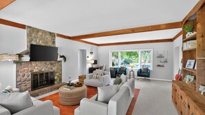 A spacious living room with a stone fireplace, a large TV mounted on the wall, and a cozy seating area with a round coffee table. - Secluded Luxe 5BR Estate Pool, Wineries, Near ND (Niles)