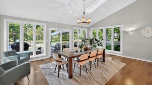 A spacious dining area with a large wooden table and chairs, large windows with a view of the outdoors, and a chandelier. - Secluded Luxe 5BR Estate Pool, Wineries, Near ND (Niles)