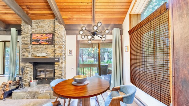 Un salon chaleureux avec une cheminée en pierre, un plafond en bois et une table à manger avec des chaises.