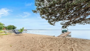 Een strand met een houten steiger, ligbedden en een klein gebouw.