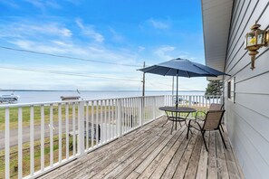 Eine Holzterrasse mit Tisch und Stühlen mit Blick auf ein Gewässer.