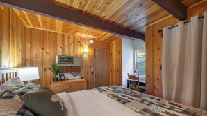 A wooden-paneled room with a bed, a desk, and a chair.